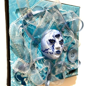 une sculpture d'un visage bleu avec trois yeux et du tissu autour