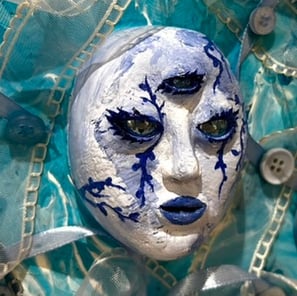 une sculpture d'un visage bleu avec trois yeux et du tissu autour