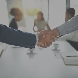 two people shaking hands in front of a table