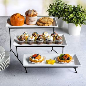 A sleek and modern 3-tier white porcelain plate set with a black metal stand, perfect for serving