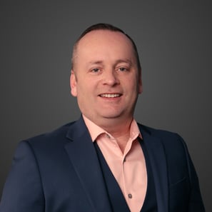 a man in a navy suit and pink shirt