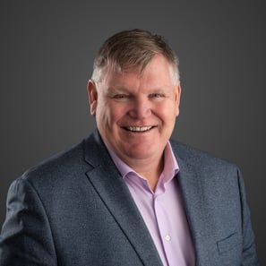 a man in a grey suit and pink shirt