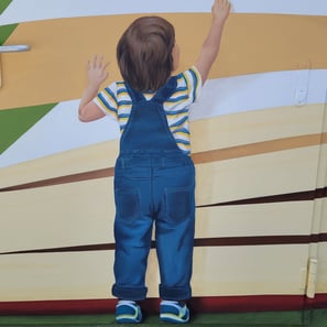 Détail d'une fresque murale: un garçon debout de dos se hisse sur la pointe de pieds. Viry, Jura.