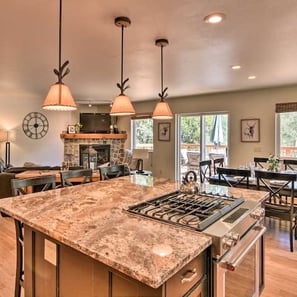  Open-concept kitchen and living room with large granite island, gas range, and fireplace.
