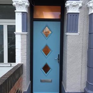 A narrow door fitted in Portsmouth by buildmydoor. the door is duck egg blue with 3 diamonds and a top light