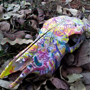 peinture aux couleurs vives sur un crane sur un lit de feuilles mortes