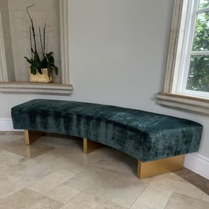 Custom curved bench with emerald green velvet upholstery and gold-painted wooden legs, handcrafted by Solo Home Decor.