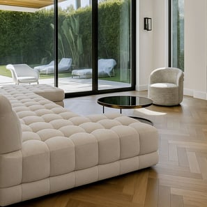Modern living room with tufted beige sofa, round coffee table, and large glass doors to patio
