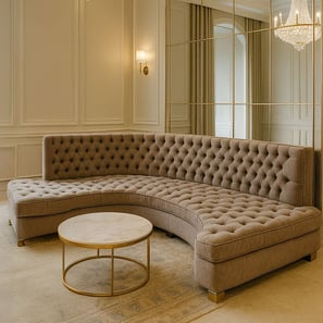 Luxurious curved tufted sofa in a transitional living room with chandelier, mirror, and soft lighting.