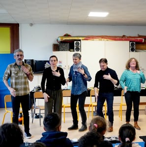 un groupe de musiciens fait des percussions corporelles devant des enfants dans une école