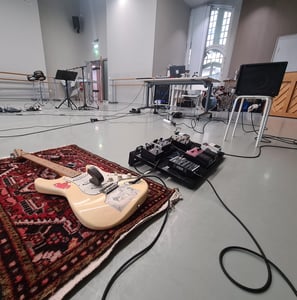 une guitare électrique et un pedalboard, avec pédales d'effets et ampli installés pour un atelier