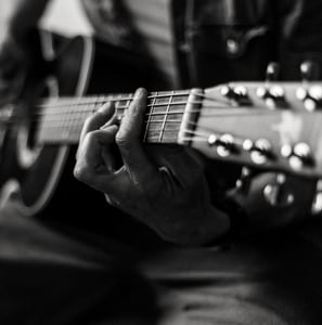 gros plan sur les mains d'un homme jouant de la guitare acoustique
