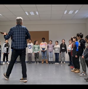 un musicien intervenant joue de la guitare en pleine séance musique avec des enfants dans une école