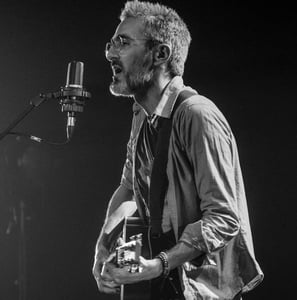 un homme chante et joue de la guitare devant un micro lors d'un concert