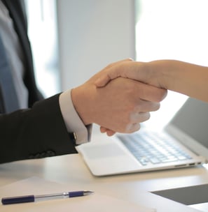 a man and woman shaking hands over a laptop