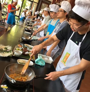 a group of people participating in thai cooking classs