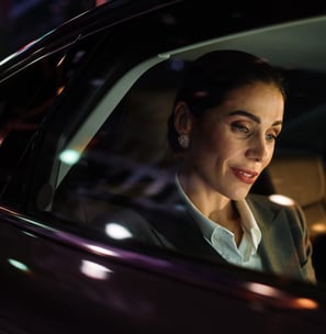 Empresária usa o celular enquanto está em um carro de transferência em uma rua urbana com letreiros