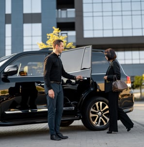 O motorista ajuda um casal de empresários a entrar no carro, abrindo a porta de um táxi preto de lux