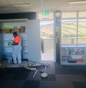 a man in a orange shirt is standing in front of a refrigerator
