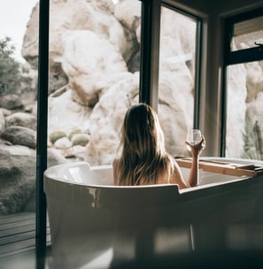 Frau in einer Badewanne mit einem Glas Wein in der Hand