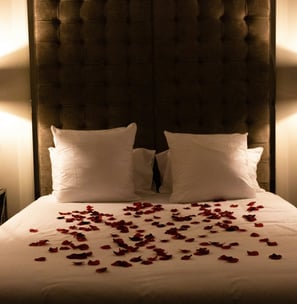 Bett mit Rosenblüten bedeckt