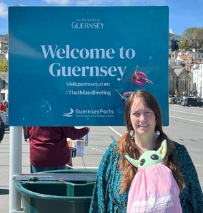 Woman in front of sign that says "Welcome to Guernsey"