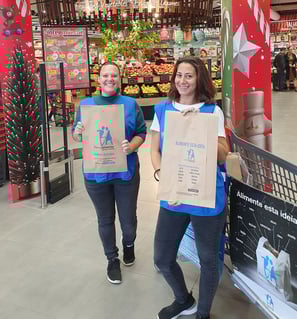 Two female volunteers helping with a food bank campaign in Alvor, holding bags for food donations