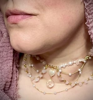 a woman in pink hijab wearing a delicate multi-chain necklace with rose quartz and pearl beads