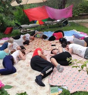 a group of people sitting on a blanket on a blanket, rilassamento, classe bioenergetica
