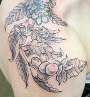 a woman with a tattoo on her chest and shoulder delicate leaf design