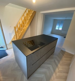 cuisine contemporaine, aspect béton cirée et plan noir roche en slim, un escalier bois clair 