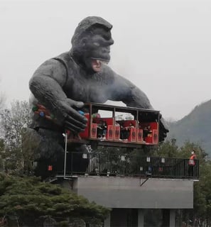 a giant gorilla statue of a gorilla sitting amusement equipment on top of a building