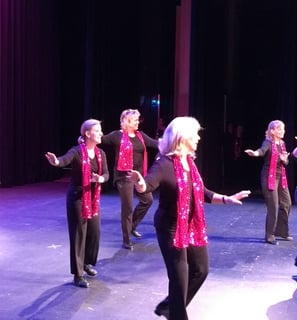 a group of women tap dancers in pink and black outfits on stage