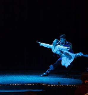 a boy and girl dancing on stage in a show of the Nutcracker.
