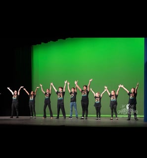 a group of kids in a musical theatre class dancing on a stage