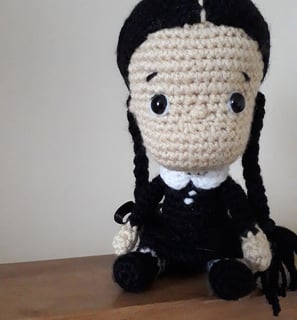 Amigurumi character doll in the style of Wednesday Adams. Crocheted goth doll.