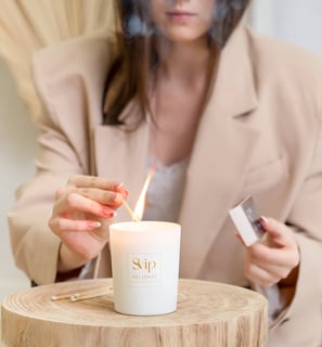 a woman is holding a match and burning a candle