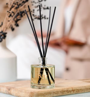 a glass bottle of home scent with a wooden board on a table