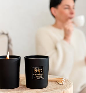 a woman sitting on a table with a cup of coffee and a candle is burning