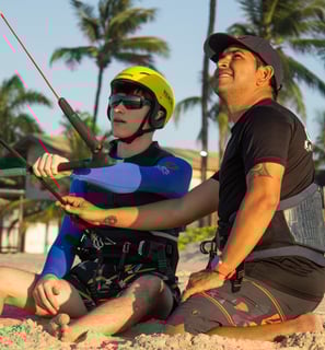 adolescente fazendo aula de kitesurf ao lado do instrutor.