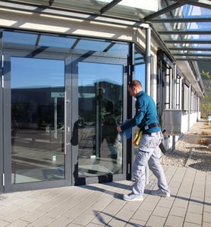 Ein Fensterputzer reinigt eine große Glasfront an einem Gebäude. 