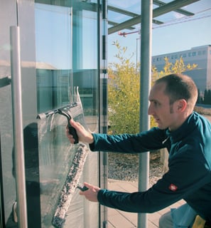 Ein Fensterputzer reinigt eine große Glasfäche. 