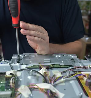 Close-up of hands performing intricate circuit board repair on a TV