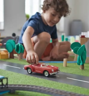 enfant qui joue avec une voiture rouge