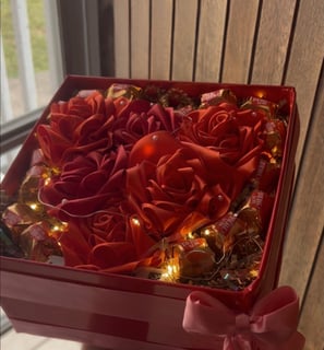 a person holding a red box with roses in it