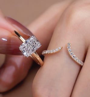 The image features two elegant rings worn on a woman’s fingers, showcasing a modern and luxurious je