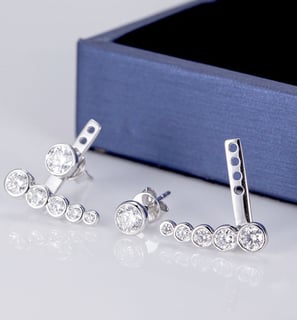 The image showcases a modern and elegant pair of silver or white gold ear climber earrings, featurin