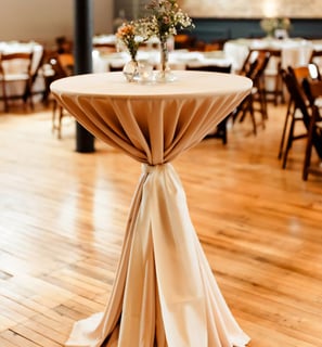 Mesa de coctel en un salon decorada con un mantel y flores