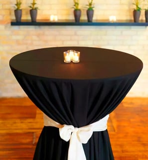 Mesa de coctel decorada con un mantel obscuro