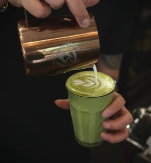 pouring a tulip on a matcha latte